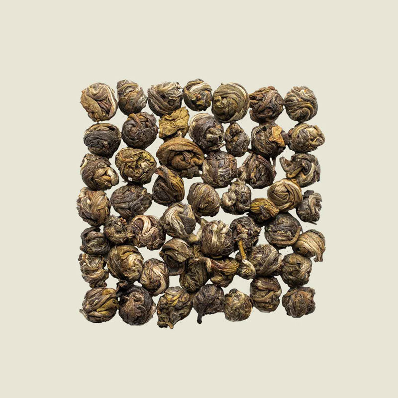 Rund gerollte Jasmin Dragon Pearls lose aufgelegt, florales Aroma sichtbar – Draufsicht auf eleganten Grüntee von Noema.